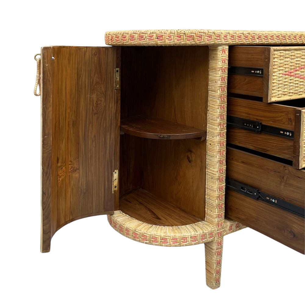 A tropical-style wooden cabinet with a warm brown wood finish and woven rattan trim, shown with its door open to reveal a shelf inside and drawers on the right.